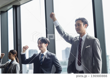 ガッツポーズをするスーツ姿の若い男女 136980866