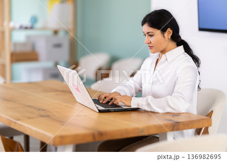 Female works on laptop in room Female works on laptop in room 136982695