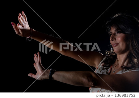 Open hands gesture, Woman extends palms toward viewer, Inviting connection through open hand gesture, Expressing emotional openness in subdued studio environment Open hands gesture, Woman extends palms toward viewer, Inviting connection through open hand gesture, Expressing emotional openness in subdued studio environment 136983752