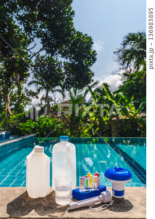 Pool water testing and chemical treatment kit on pool edge with tropical garden background Pool water testing and chemical treatment kit on pool edge with tropical garden background 136983895