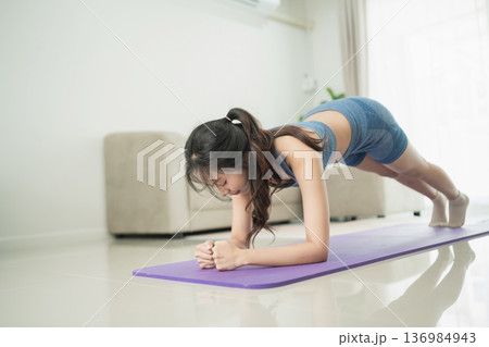 Woman Performing Plank Exercise on Yoga Mat in Modern Living Room with Natural Light and Contemporary Decor Woman Performing Plank Exercise on Yoga Mat in Modern Living Room with Natural Light and Contemporary Decor 136984943