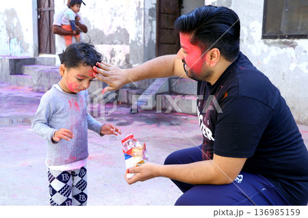 Father and Child Celebrating Holi Festival with Colored Powder Father and Child Celebrating Holi Festival with Colored Powder 136985159