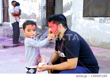 Father and Child Celebrating Holi Festival with Colored Powder Father and Child Celebrating Holi Festival with Colored Powder 136985160