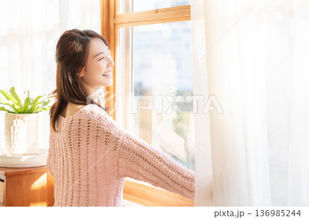カーテンを開ける女性 136985244