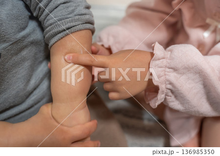 赤ちゃんの小さな腕を触る子供の手 赤ちゃんの小さな腕を触る子供の手 136985350