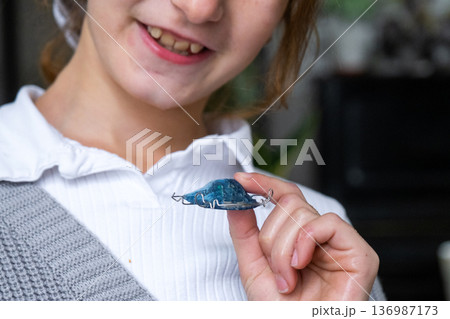 Orthodontic exam: girl demonstrates plate for teeth alignment and jaw correction, pediatric dentistry. 136987173