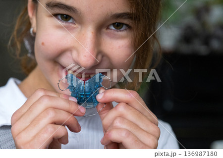 Child inserting blue orthodontic plate, step of pediatric teeth and bite correction, dental self-care. Child inserting blue orthodontic plate, step of pediatric teeth and bite correction, dental self-care. 136987180