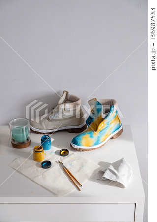 Two boots, one plain and one custom painted with blue and yellow colors. Two boots, one plain and one custom painted with blue and yellow colors. 136987583