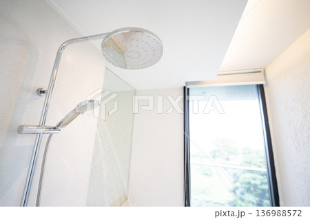 Cold Water was pouring out from a large shower in the bathroom with a glass window. Cold Water was pouring out from a large shower in the bathroom with a glass window. 136988572