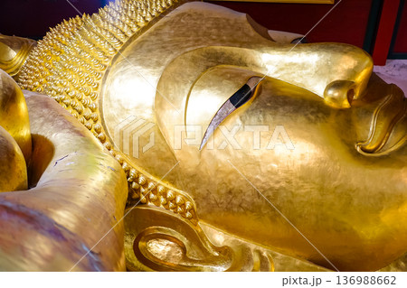 The close up face of the Reclining Buddha statue image at Wat Phra Phut Saiyat or Saiyat Buddhist temple in Phetchaburi province, Thailand. The close up face of the Reclining Buddha statue image at Wat Phra Phut Saiyat or Saiyat Buddhist temple in Phetchaburi province, Thailand. 136988662