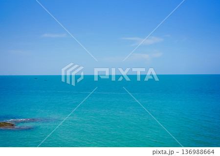 The landscape picture of the tranquil beach and azure sea at Hua Hin, Thailand with skyscraper view on the horizon line and blue sky. Beach rocks and tropical plants. 136988664