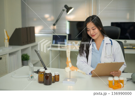 Doctor studying a bone model at a desk, showing medical learning, anatomy education, and professional training Doctor studying a bone model at a desk, showing medical learning, anatomy education, and professional training 136990000