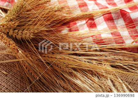 Wheat stalks and checked fabric on a burlap surface in a simple kitchen setting Wheat stalks and checked fabric on a burlap surface in a simple kitchen setting 136990698