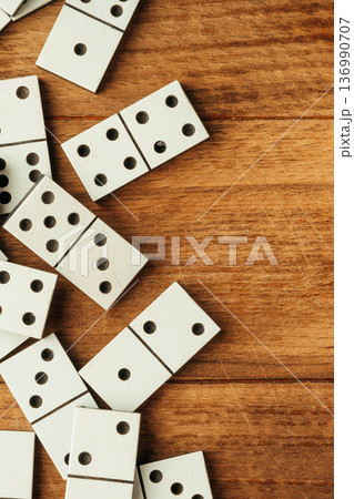 Players enjoy a game with white dominoes on a wooden table in the afternoon light 136990707