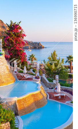 Beautiful pool area and ocean view by the coastline during sunset 136990715