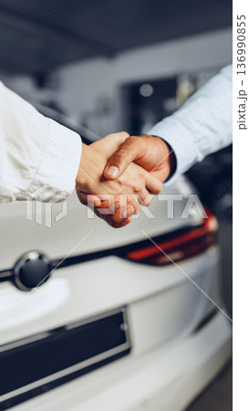 Handshake between two people at a car dealership in the morning light Handshake between two people at a car dealership in the morning light 136990855