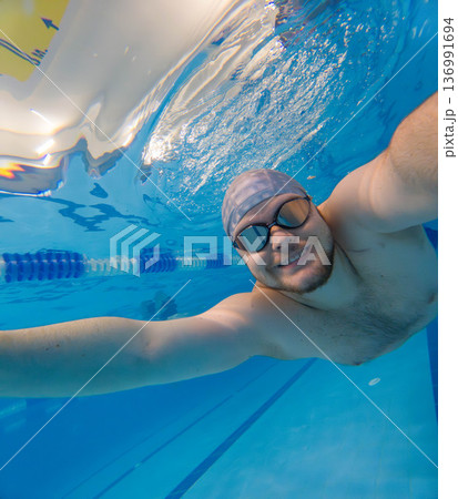 Underwater selfie of swimmer in blue pool with goggles Underwater selfie of swimmer in blue pool with goggles 136991694