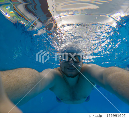 Underwater selfie of swimmer in blue pool with goggles Underwater selfie of swimmer in blue pool with goggles 136991695