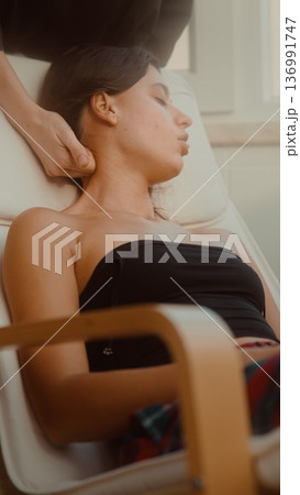 Female individual reclining peacefully while professional provides care Female individual reclining peacefully while professional provides care 136991747