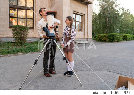 Astronomy instructor teaching telescope use to young student 136991928