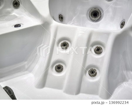 Hot tub interior with water jets and seating area for relaxation during a sunny afternoon outside a house Hot tub interior with water jets and seating area for relaxation during a sunny afternoon outside a house 136992234