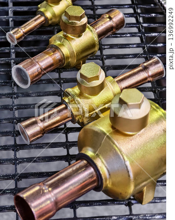 Brightly colored copper valves displayed on a metal rack in a workshop during daytime work hours 136992249
