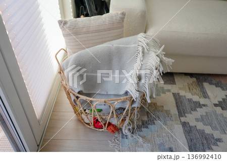 Woven rattan basket with cozy blankets and yarn in Scandinavian home interior 136992410