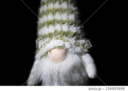Cute gnome doll with striped knitted hat on black background 136993698