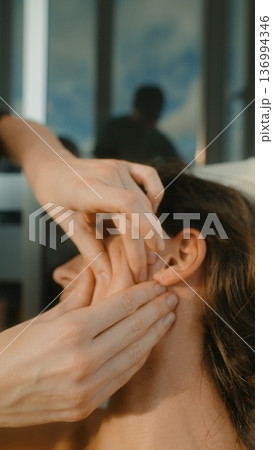 Practitioner applying gentle pressure for ear relaxation session 136994346