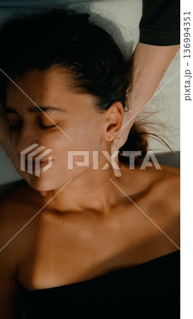 Tranquil woman receiving gentle facial treatment in soft evening light 136994351
