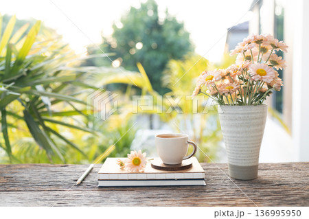 coffee cup and Chrysanthemum flowers in a vase and notebook on wooed table with garden view coffee cup and Chrysanthemum flowers in a vase and notebook on wooed table with garden view 136995950