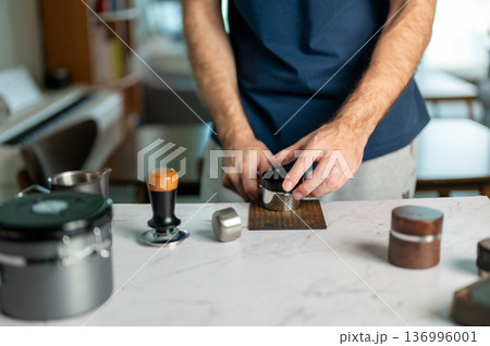 Man Tapping The Portafilter After Dosing Coffee Grounds In Kitchen 136996001