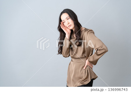 グレー背景でスキンケアをする女性ビューティー グレー背景でスキンケアをする女性ビューティー 136996743