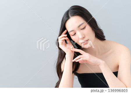 グレー背景でスキンケアをする女性のビューティーイメージ グレー背景でスキンケアをする女性のビューティーイメージ 136996803