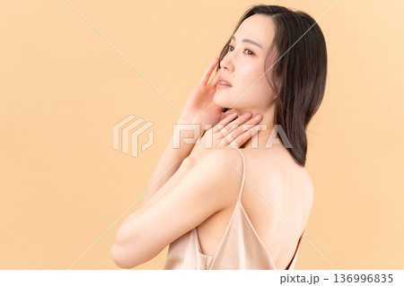 ベージュ背景でスキンケアをする女性のビューティーイメージ 136996835