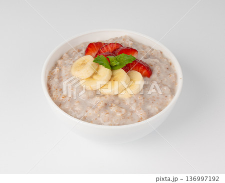 Cooked spelt in bowl isolated. Oatmeal milk porridge with fruits and berries 136997192