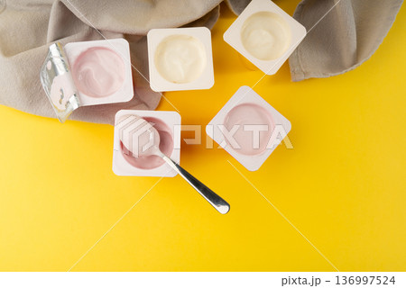 Yogurt cups set, pink and yellow fruit yoghurt in plastic pots, milk pudding container with spoon 136997524