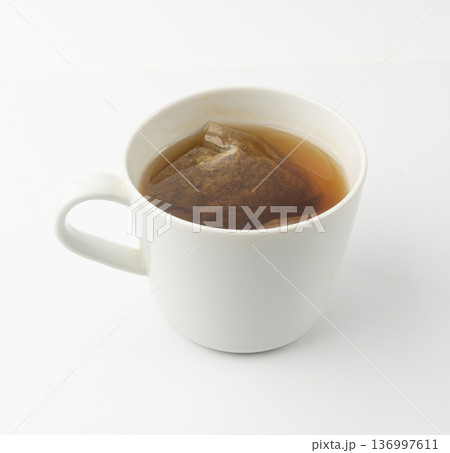 Herbal tea sachet in cup, hot water with chamomile and Hypericum or St. John's wort teabag 136997611