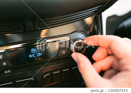 Man turning on car air conditioning system Man turning on car air conditioning system 136997834
