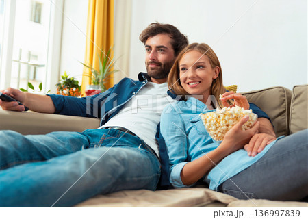 Couple watching TV on a sofa at home 136997839