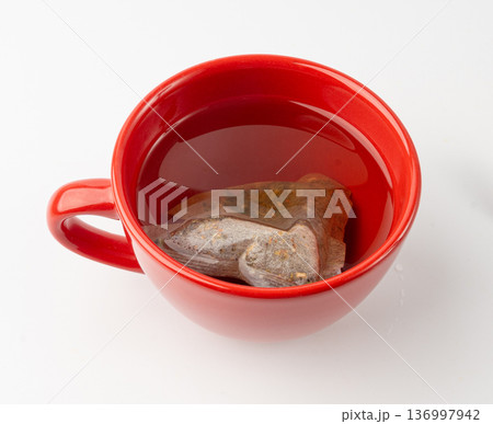 Herbal tea sachet in cup, hot water with chamomile and Hypericum or St. John's wort teabag Herbal tea sachet in cup, hot water with chamomile and Hypericum or St. John's wort teabag 136997942