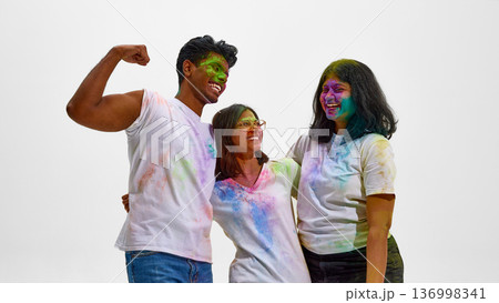 Young Indian friends celebrating Holi with joy isolated on white. 136998341