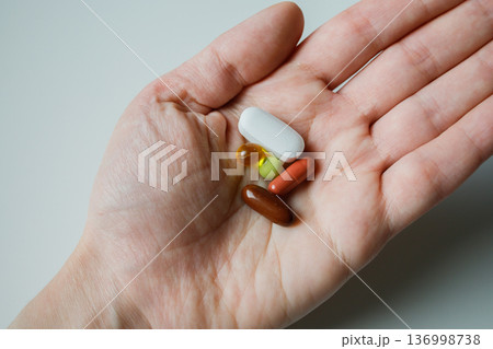 Different medical pills and capsules in woman hand close up. Medical pharmaceutical treatment at home. Daily dose of vitamins and supplements, biohacking. Different medical pills and capsules in woman hand close up. Medical pharmaceutical treatment at home. Daily dose of vitamins and supplements, biohacking. 136998738