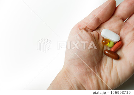 Colorful pills, tablets, capsules in woman hand close up with white background. Healthcare and medicine. 136998739