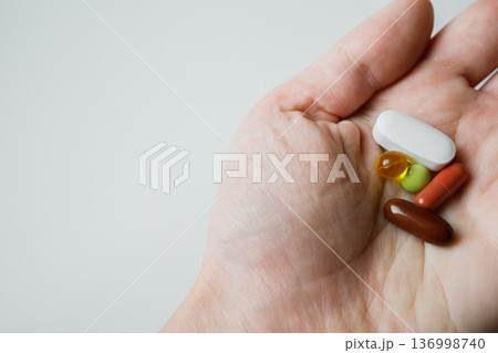 Colorful pills, tablets, capsules in woman hand close up with white background. Healthcare and medicine. 136998740