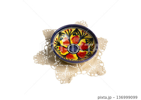 a small hand-painted bowl on a crocheted doily 136999099