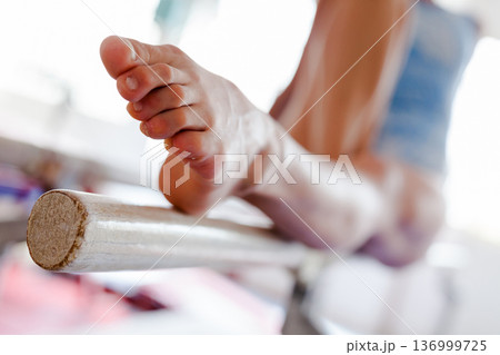 Bare tensed feet of female gymnast performing on parallel bars Bare tensed feet of female gymnast performing on parallel bars 136999725