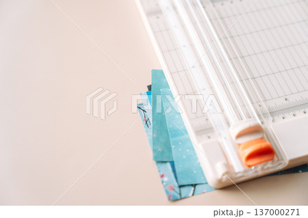 Paper trimmer with blue paper stack, craft workspace close up with copy space Paper trimmer with blue paper stack, craft workspace close up with copy space 137000271