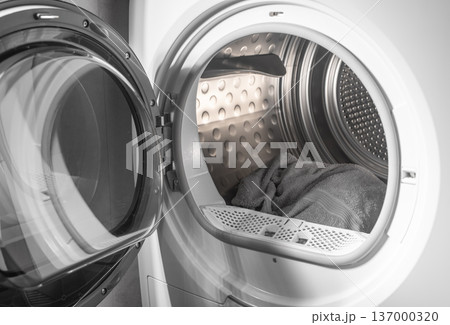 Laundry towels inside dryer drum open door. Textile lying in appliance front view. Household drying process concept.. 137000320
