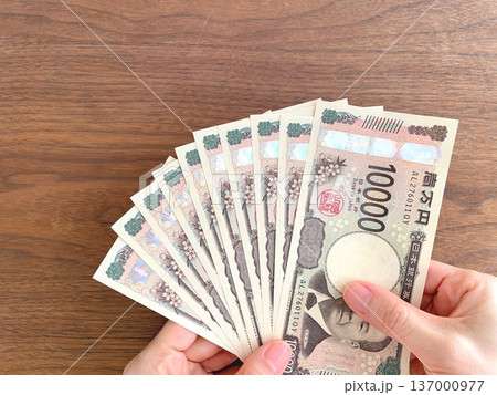 机上で10万円を持つ女性の手 机上で10万円を持つ女性の手 137000977